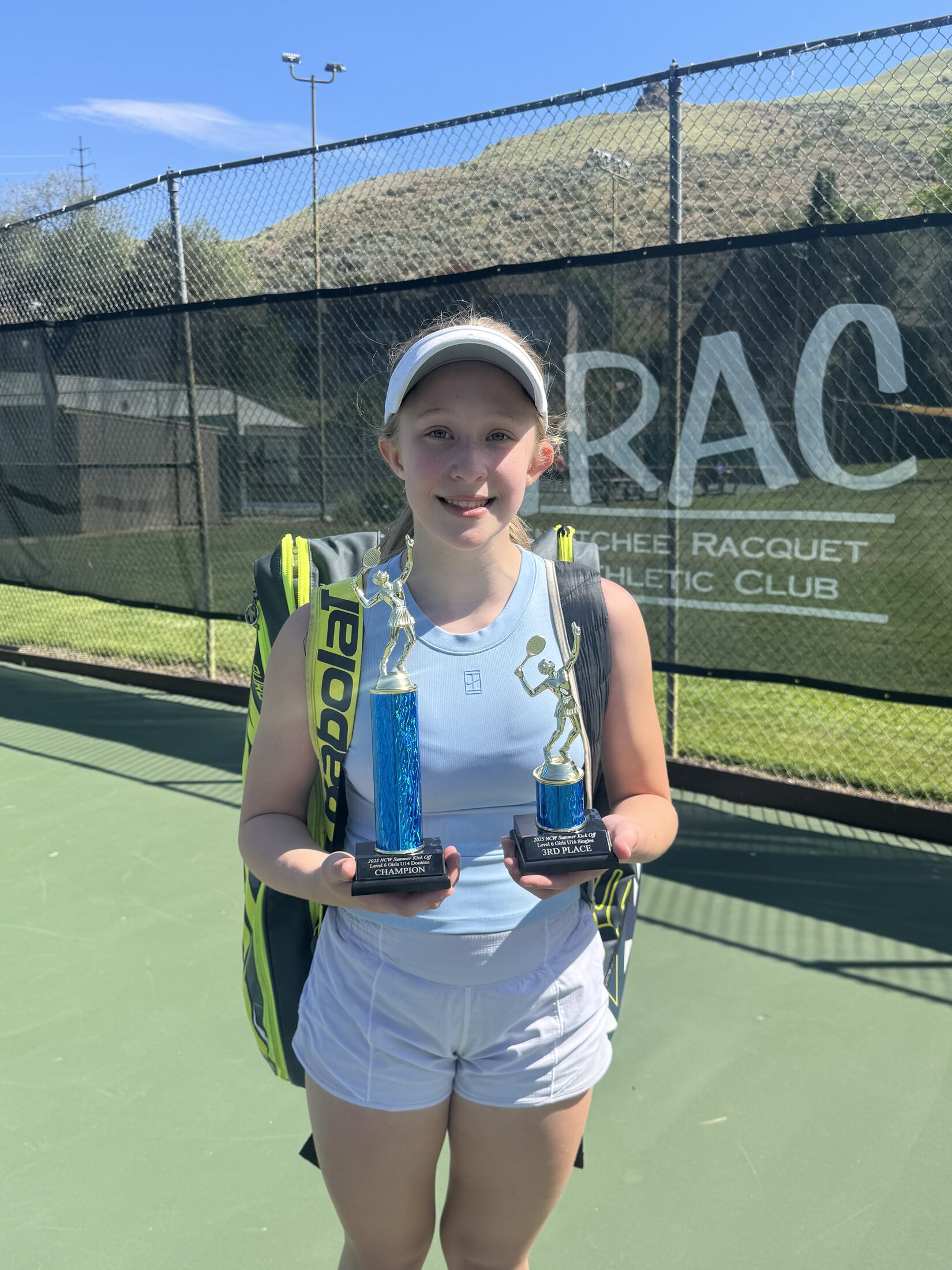 Tier 1 junior tennis player holding trophies after competition