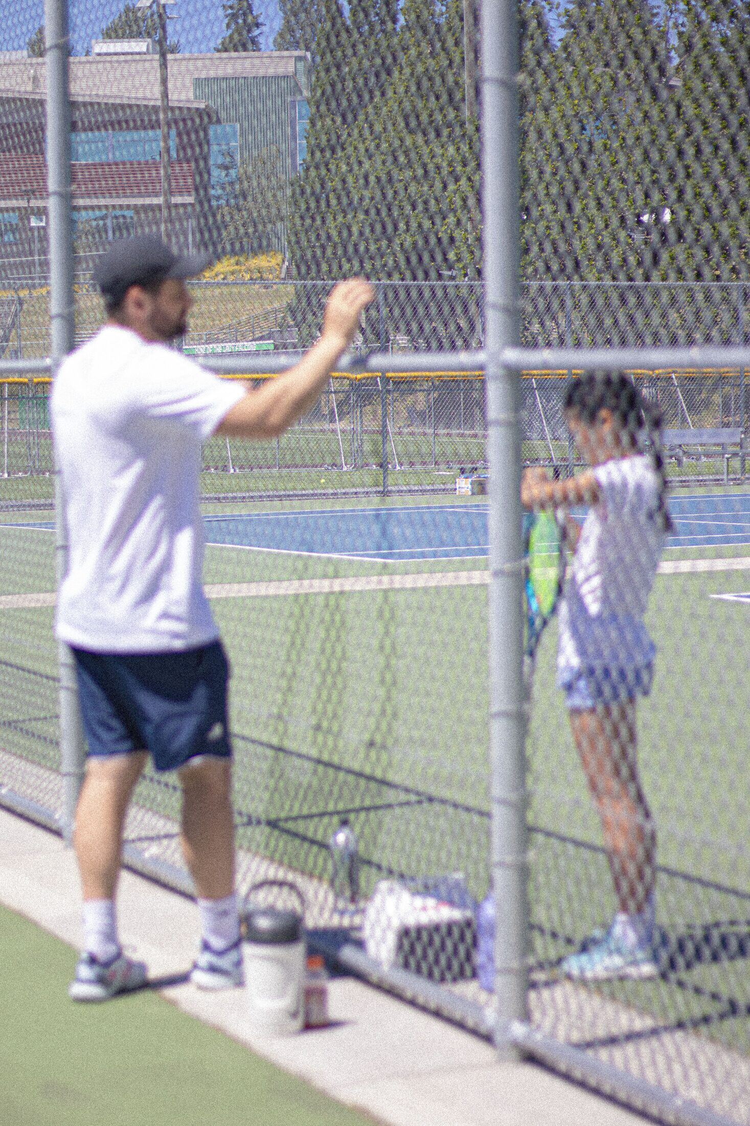 Tier 1 coach working with a young player through the court fence